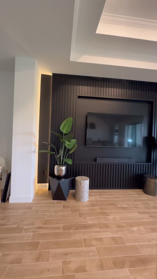 Black vertical slat wall with a recessed niche containing a mounted television and soundbar.