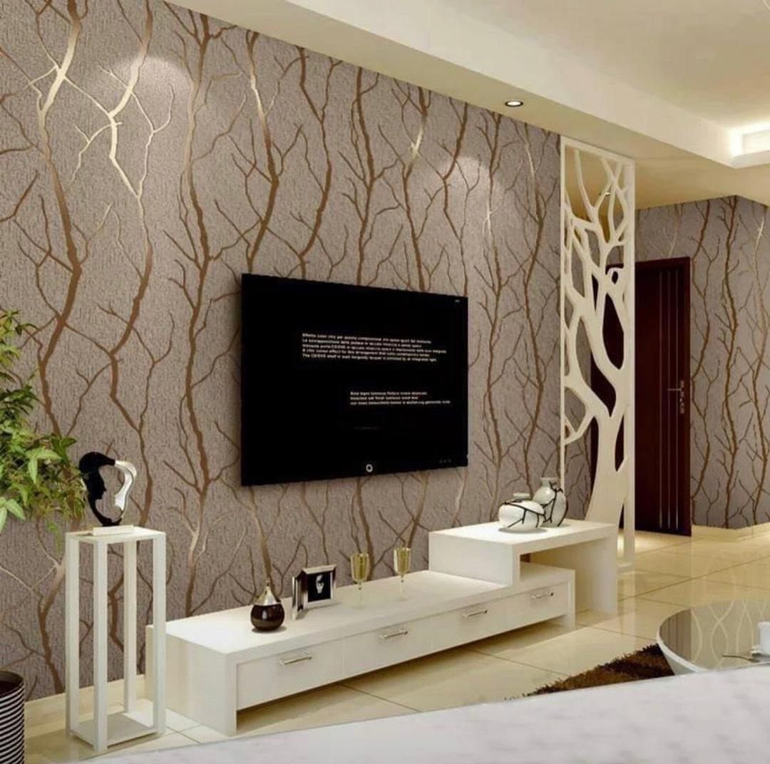 Television mounted on a beige wallpapered wall with gold branch patterns and a white media console below.