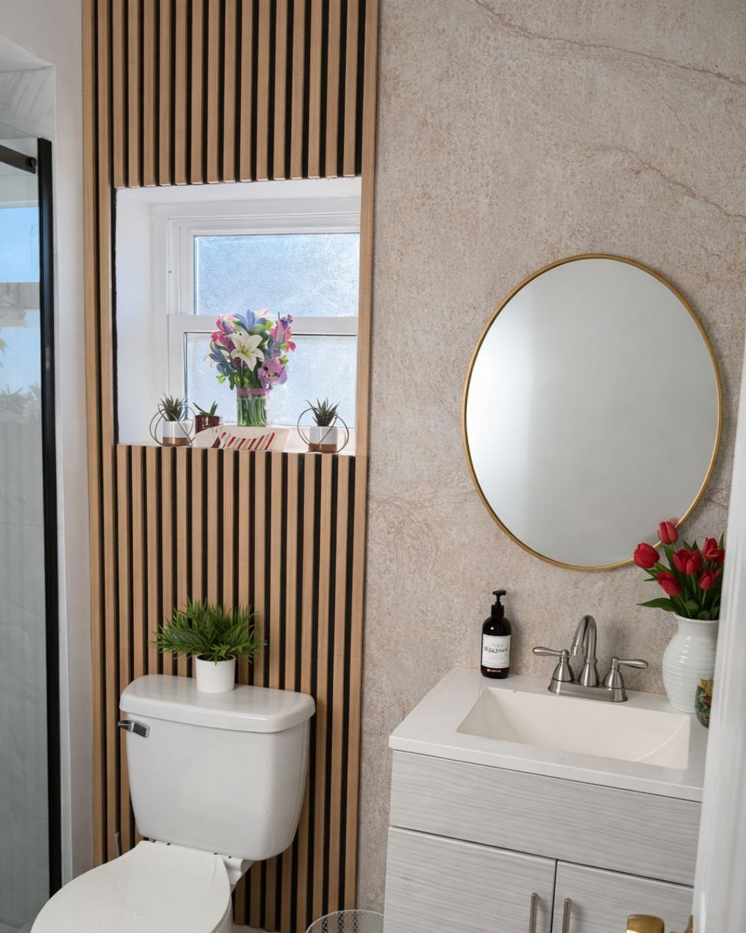 Vertical light wood slats on a bathroom wall next to a white vanity and toilet.