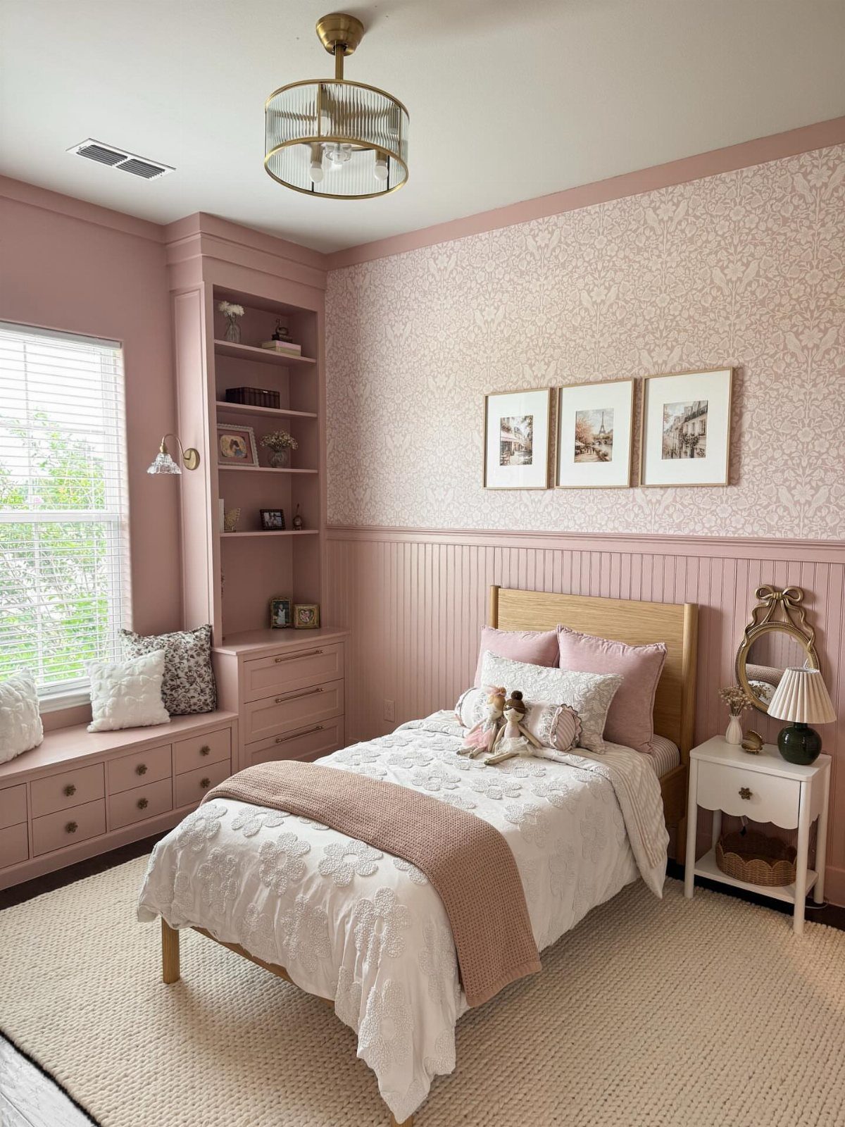 Blush pink vertical beadboard wall paneling in a child's bedroom with a small bed.