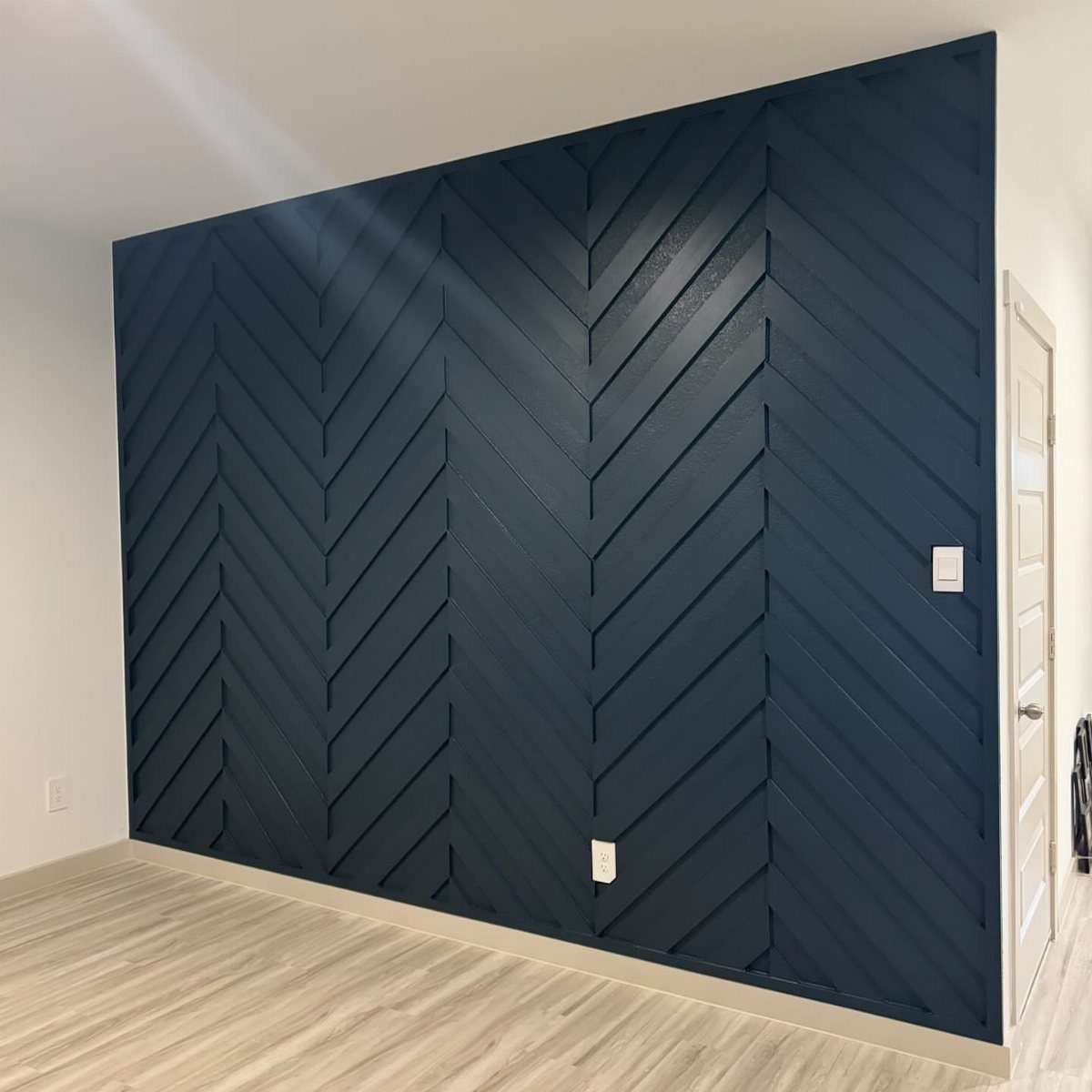 Dark navy blue accent wall with a wooden chevron pattern trim and light flooring.