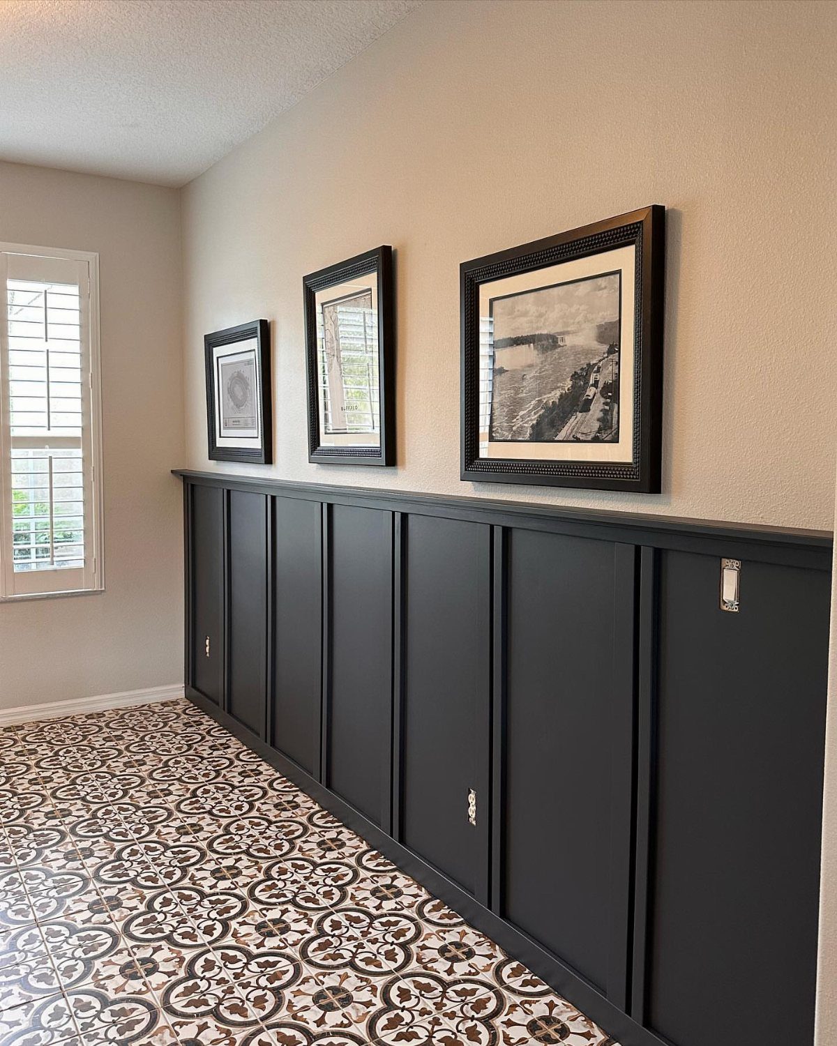 Dark grey wainscoting with vertical trim panels installed on a beige hallway wall.