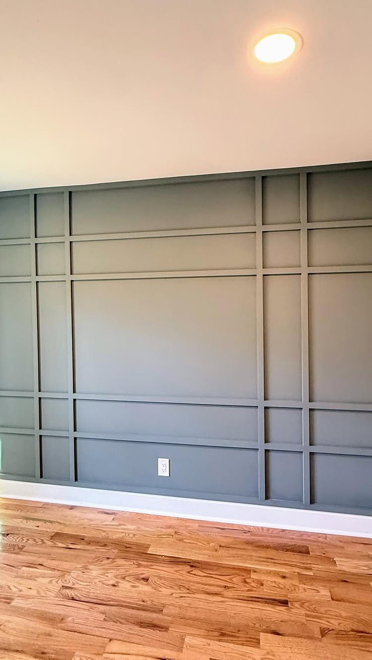 Grey wall with a modern grid pattern made of symmetrical wooden trim molding.