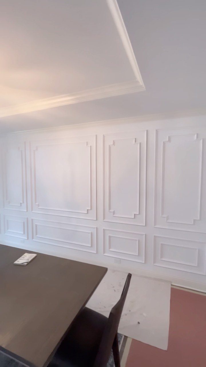 White wall decorated with elegant rectangular picture frame molding and geometric trim patterns.