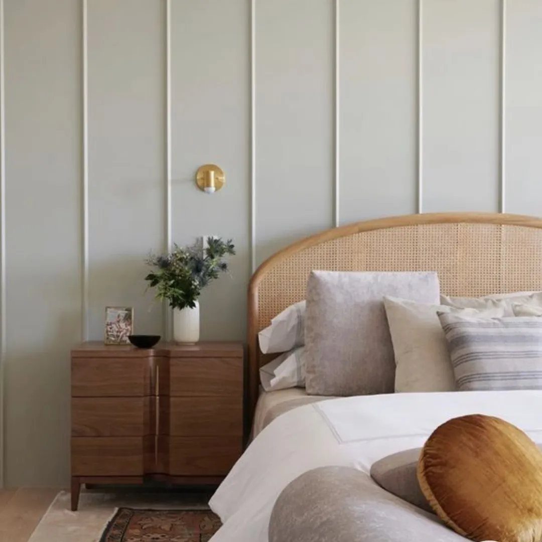 Vertical white trim strips on a light grey wall behind a bedroom nightstand and bed.