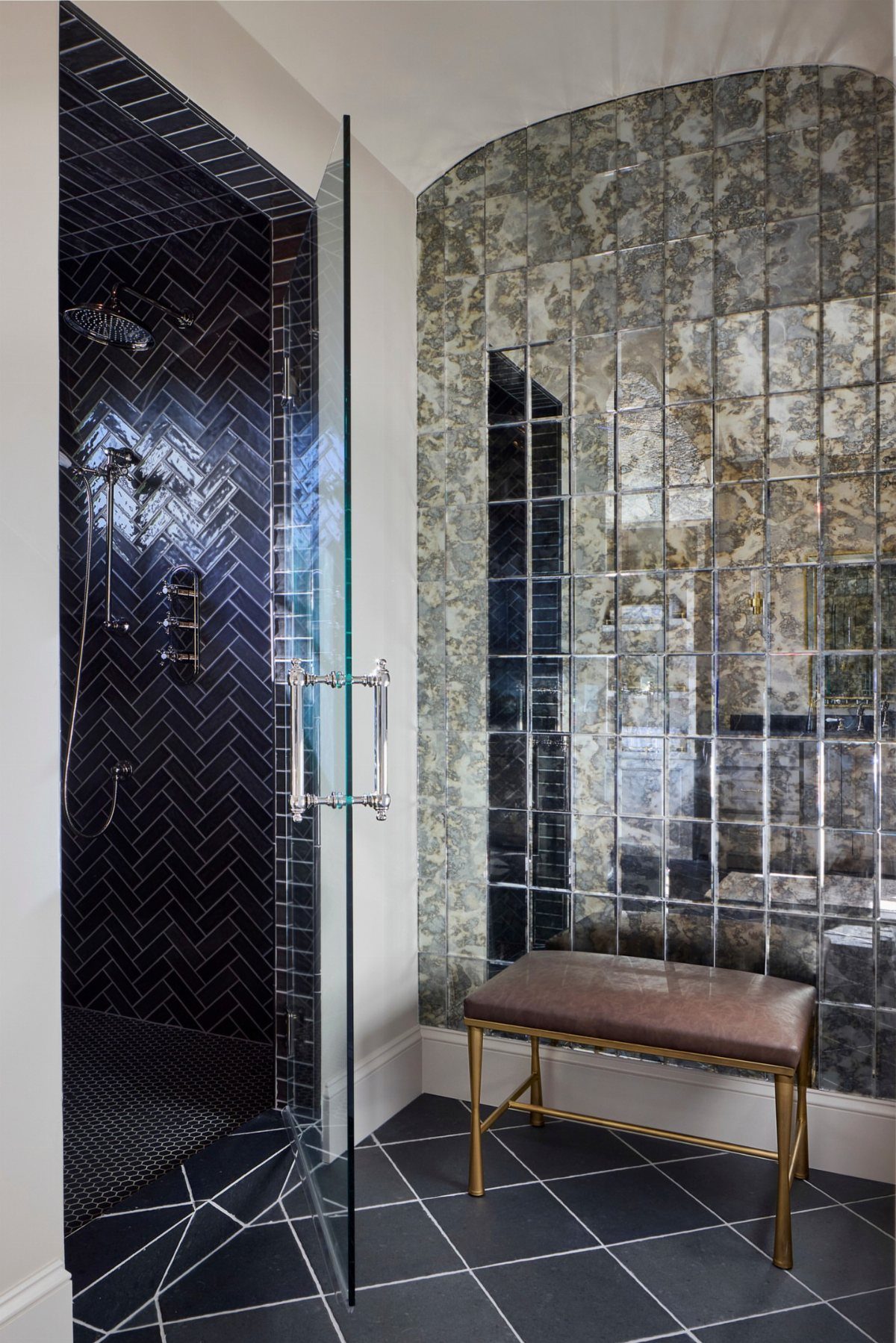 Antique mirror tiles covering a large bathroom wall next to a dark tiled shower.