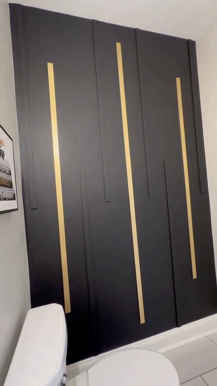 Black vertical wall planks with thin gold inlay strips in a bathroom setting.