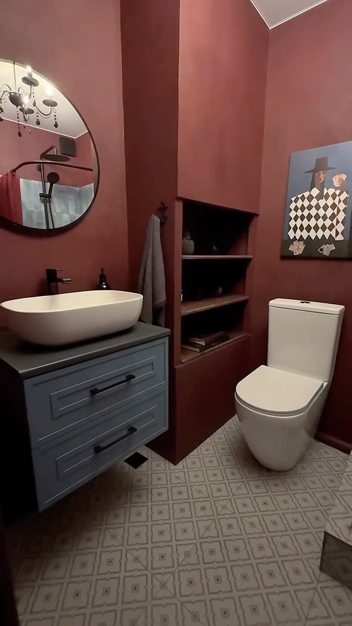 Terracotta colored bathroom walls with a white vessel sink and blue vanity cabinet.