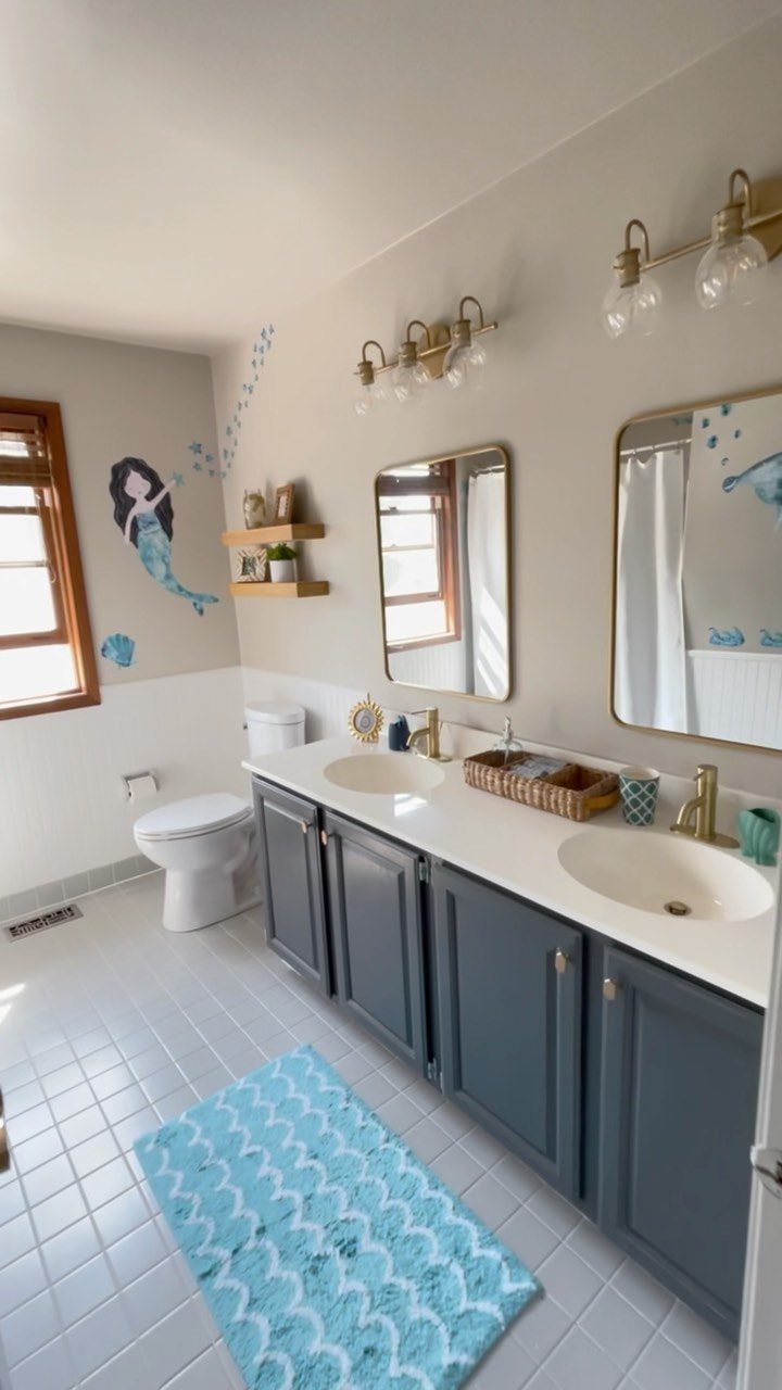 Mermaid wall decals decorating a light gray bathroom wall above a white toilet and vanity.