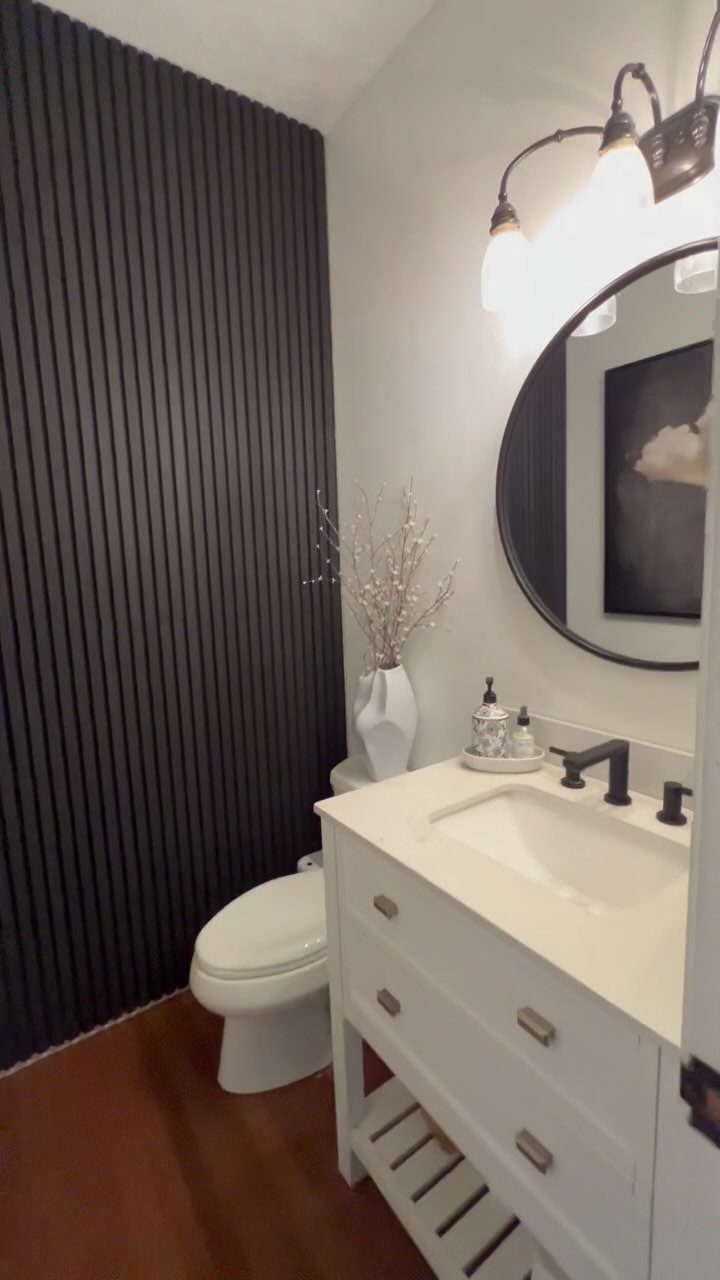 Dark vertical slatted wood panels form a bold accent wall in a modern bathroom.
