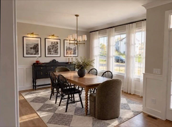 Wooden dining table with mismatched black and upholstered chairs on a patterned rug.