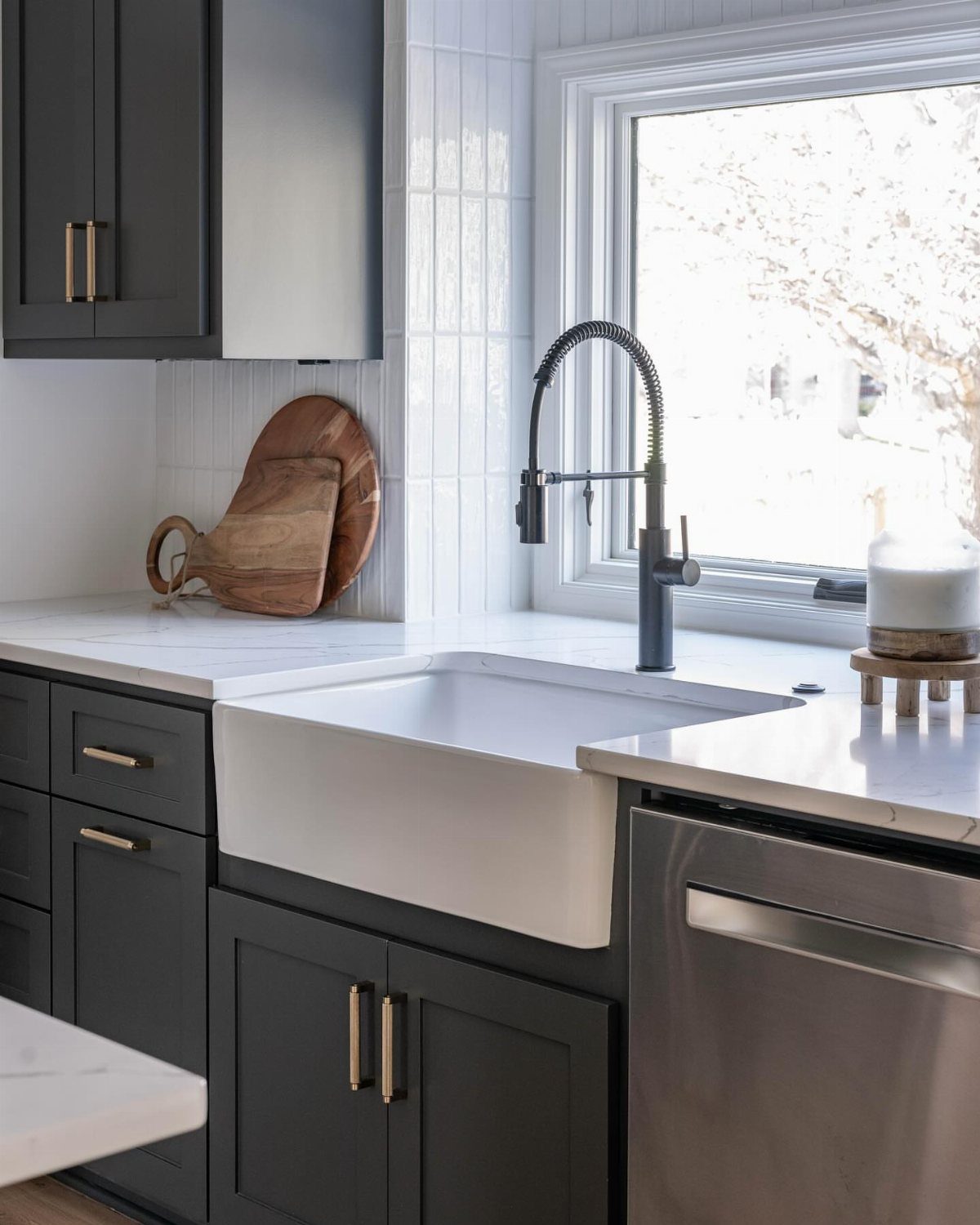 White farmhouse apron-front sink installed in a modern kitchen with dark grey cabinets.