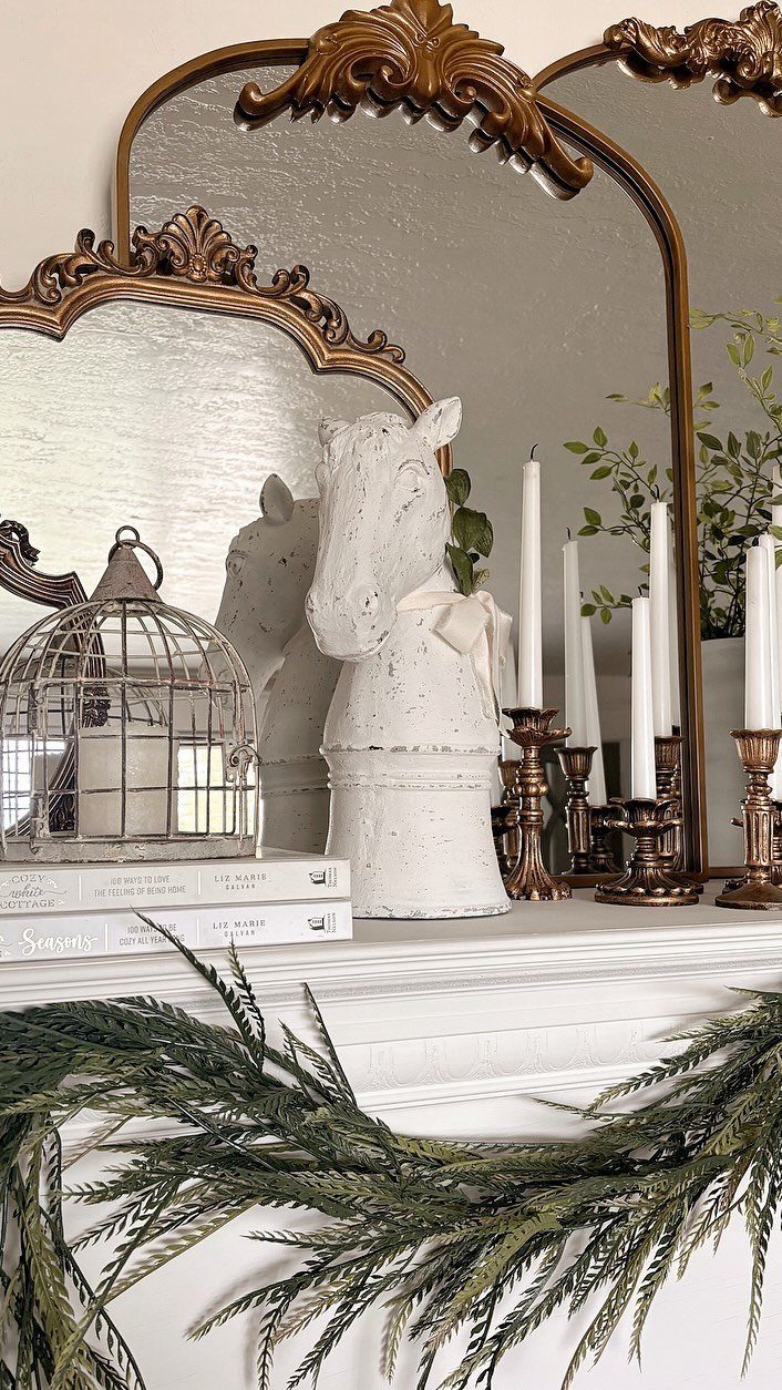 Ornate gold vintage mirrors and a white ceramic horse sculpture on a white mantelpiece.