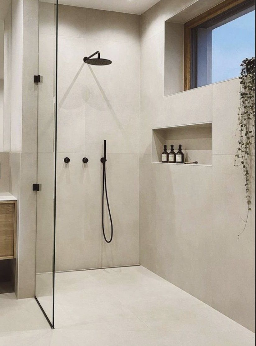 Large light-colored tiles covering the floor and walls of a modern walk-in shower.