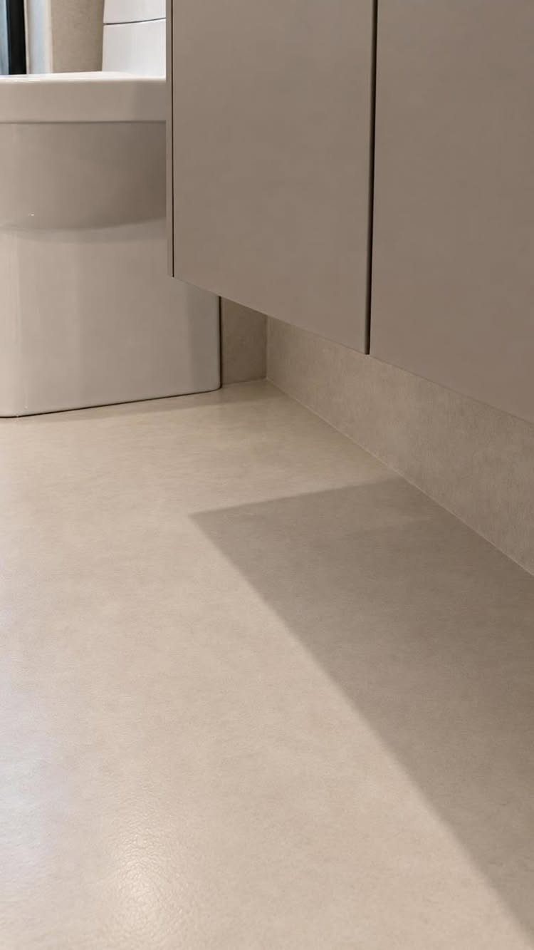 Seamless light beige microcement flooring and walls in a modern bathroom setting.