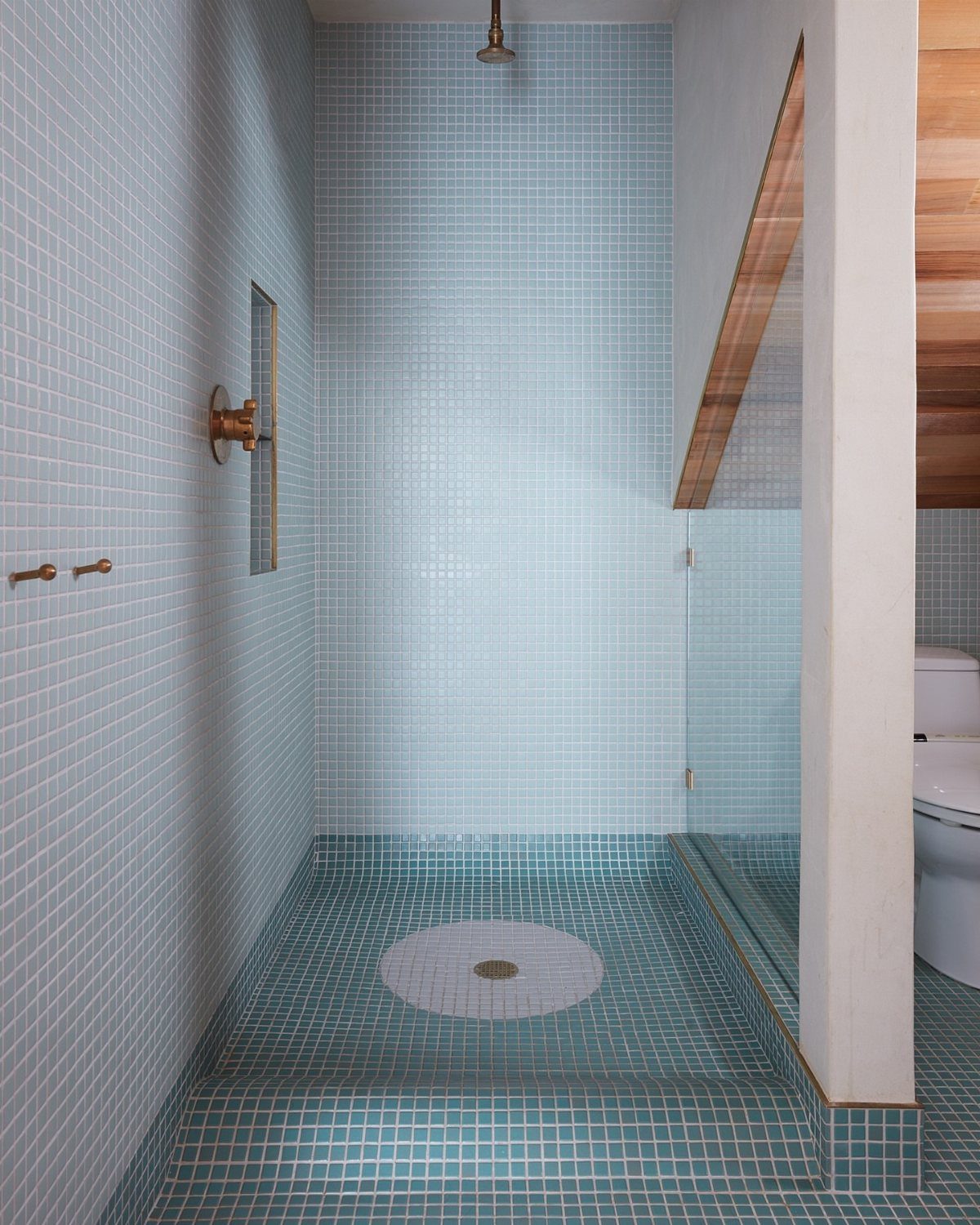 Light blue mosaic tiles covering the floor and walls of a modern walk-in shower.