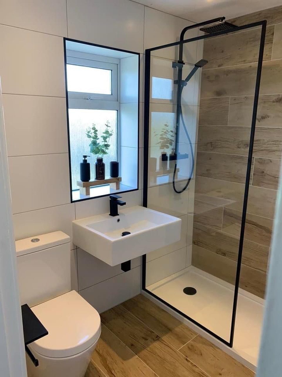 Wood-effect floor tiles in a small modern bathroom with a white sink and shower.