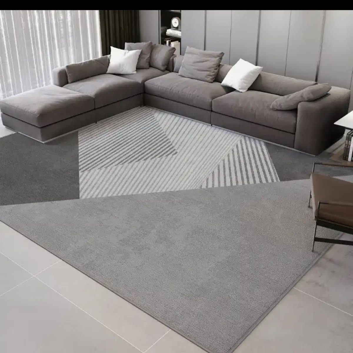 Grey sectional sofa on a large geometric patterned rug in a modern living room.