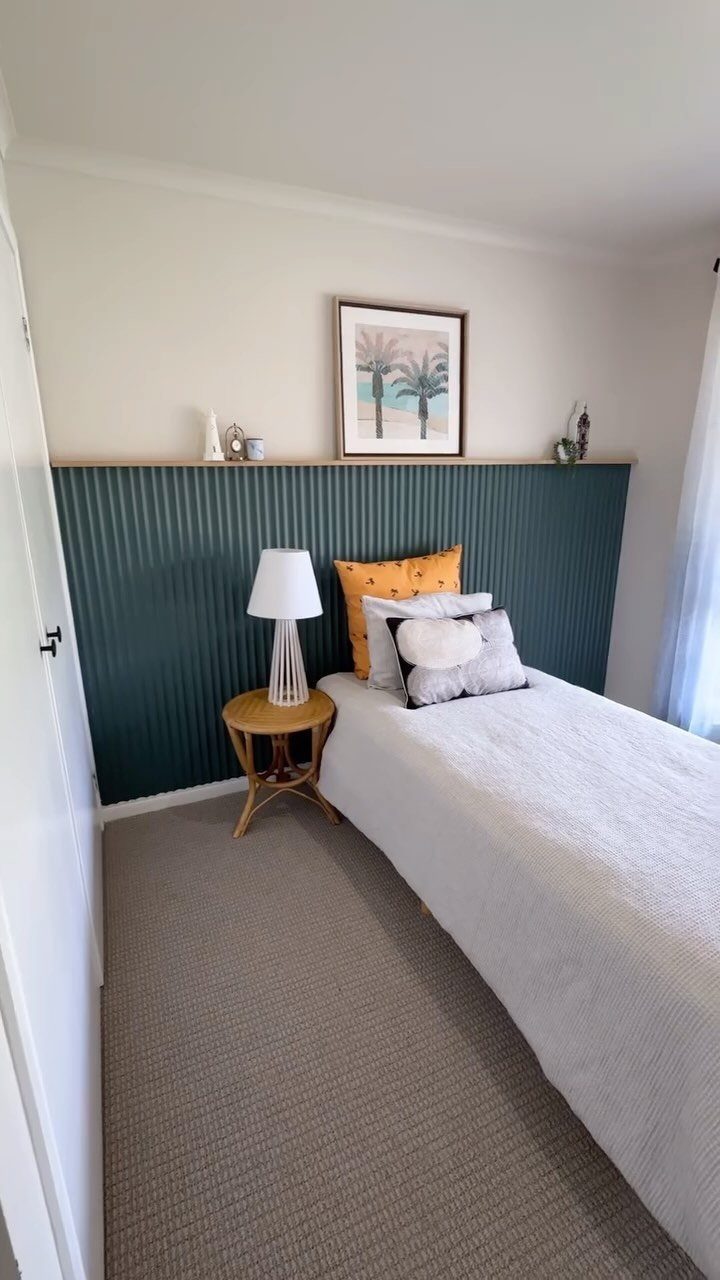 Teal curved tambour paneling serves as a headboard behind a bed in a modern bedroom.