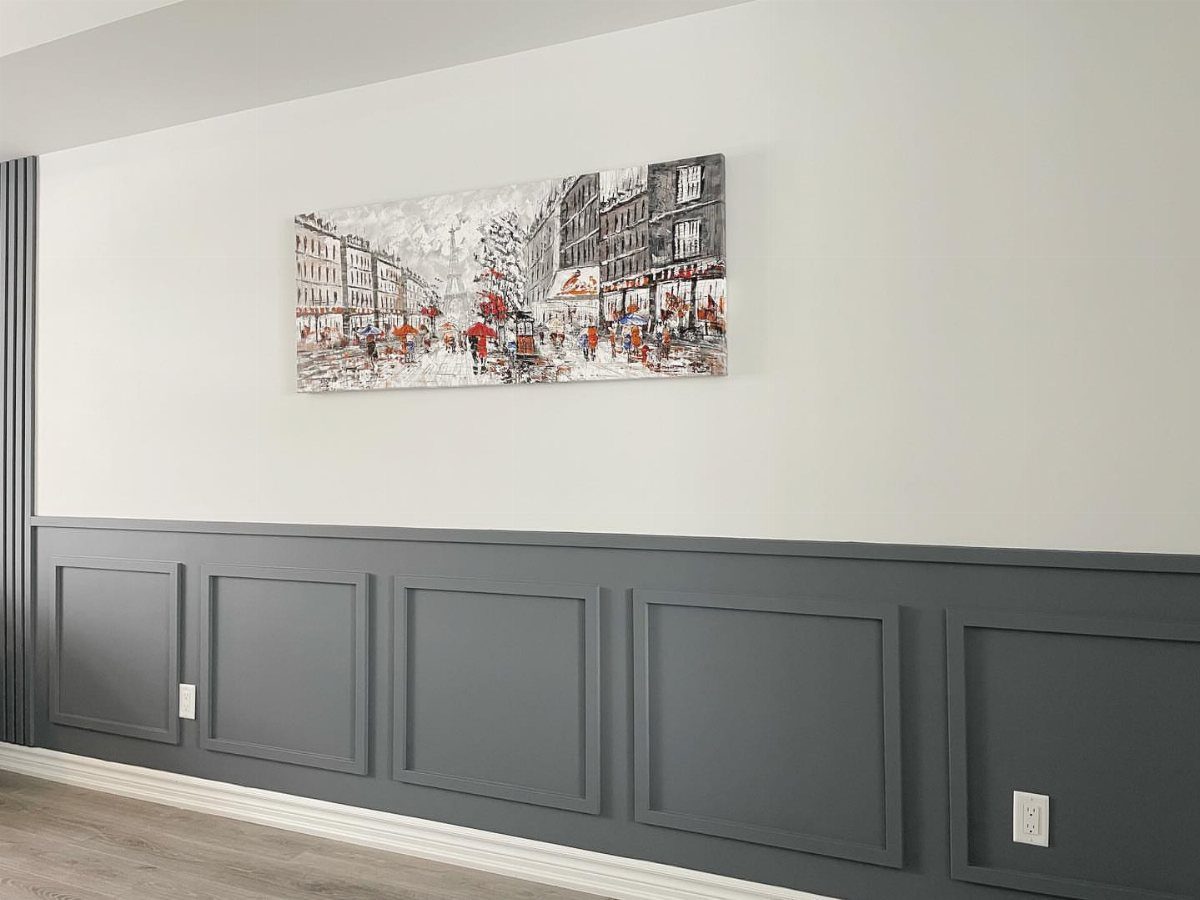 Dark grey rectangular wall paneling installed on a white wall below a city street painting.