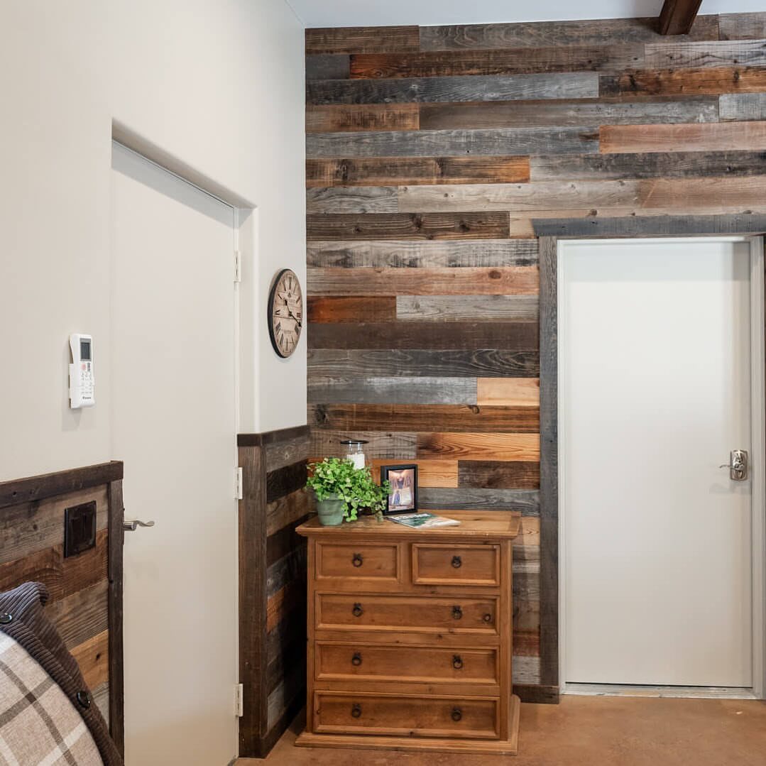 Horizontal reclaimed wood planks covering a wall in a room with a wooden dresser.