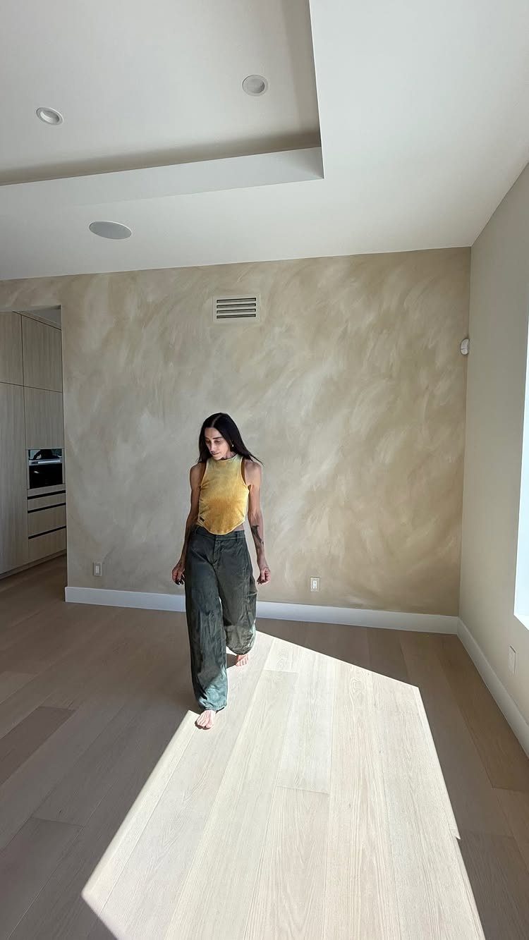 Interior Wall Design: 5 Rooms That Climb Off the Surface 3 A woman walking across a light wood floor in a room with a limewash accent wall.