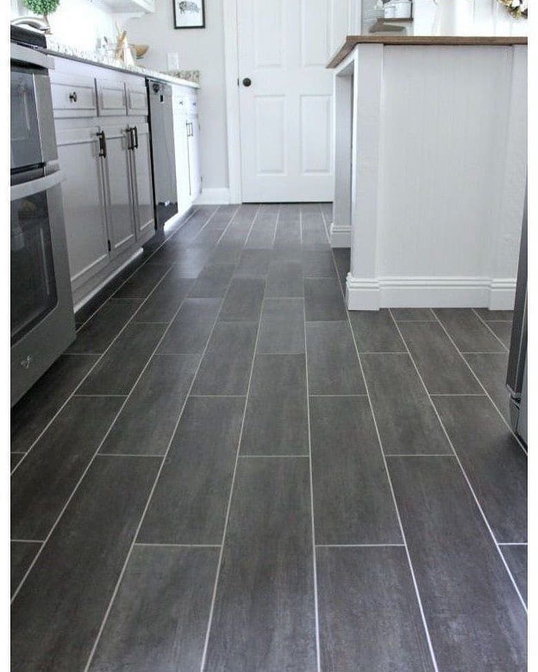 Kitchen Flooring for White Cabinets: 11 Ideas That Actually Work 10 Dark grey tiled flooring in a kitchen with white cabinets and stainless steel appliances.