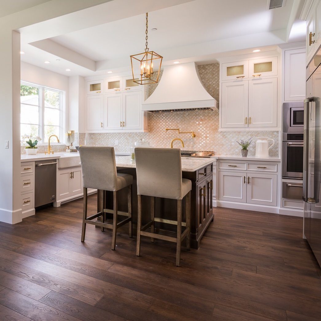 Kitchen Flooring for White Cabinets: 11 Ideas That Actually Work 2 Dark hardwood flooring in a bright kitchen with white cabinets and a central island.