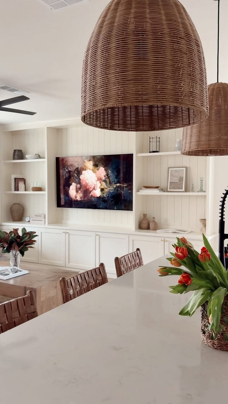White built-in cabinets with open shelving and a television mounted in a bright living area.