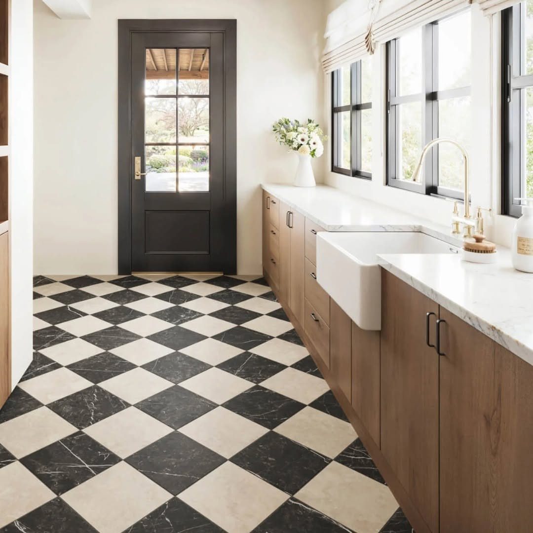 Black and cream marble checkerboard tiles on a kitchen floor with wooden cabinetry.