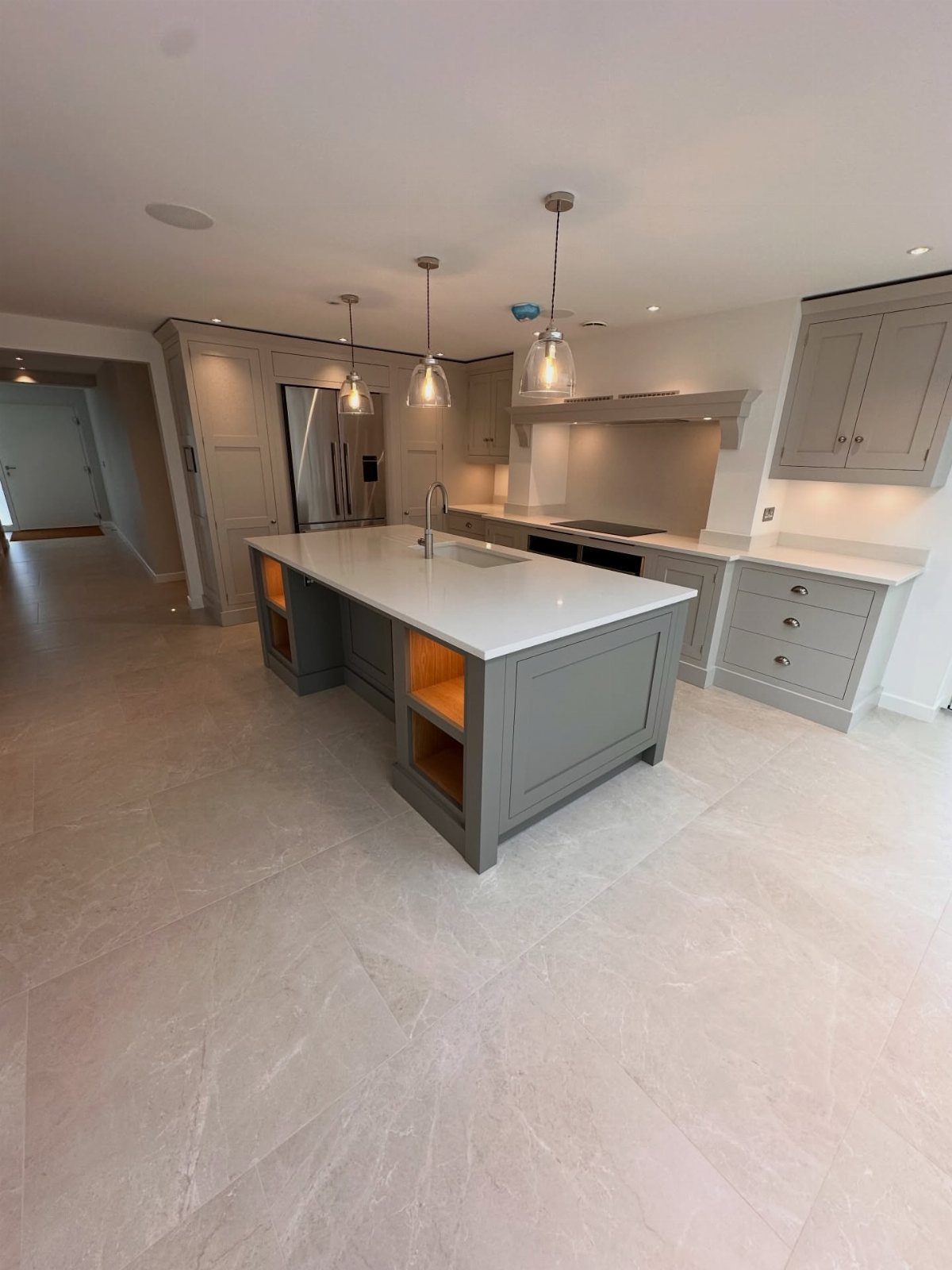 Large light grey stone-effect tiles covering the floor of a modern grey kitchen.