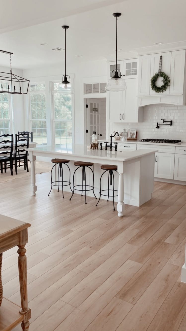 Light wood plank flooring in a bright, modern farmhouse style kitchen with a white island.