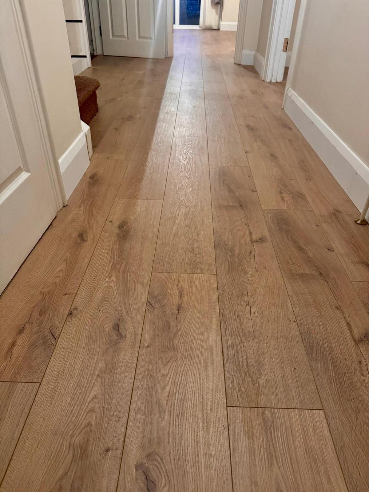 Light brown wood-effect vinyl planks installed in a hallway between white walls.