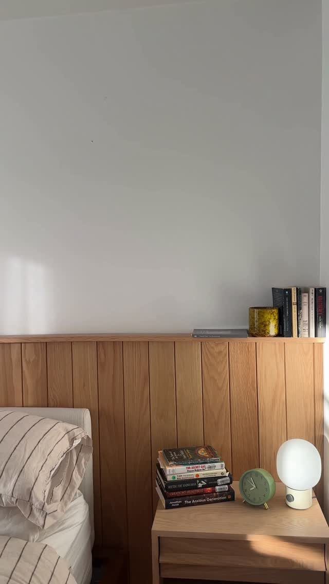 Light wood vertical paneling on a bedroom wall behind a wooden nightstand.