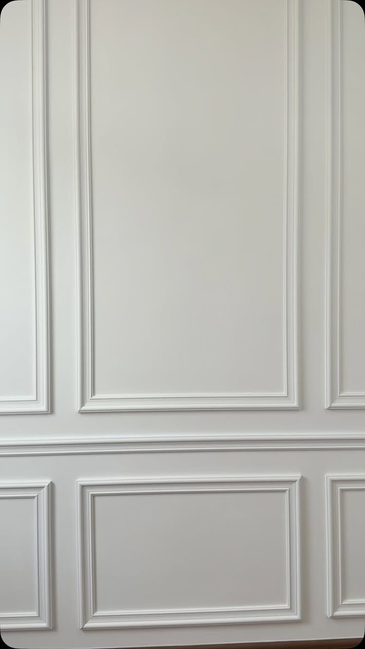 White wall panels featuring classic picture frame wainscoting with decorative rectangular molding.