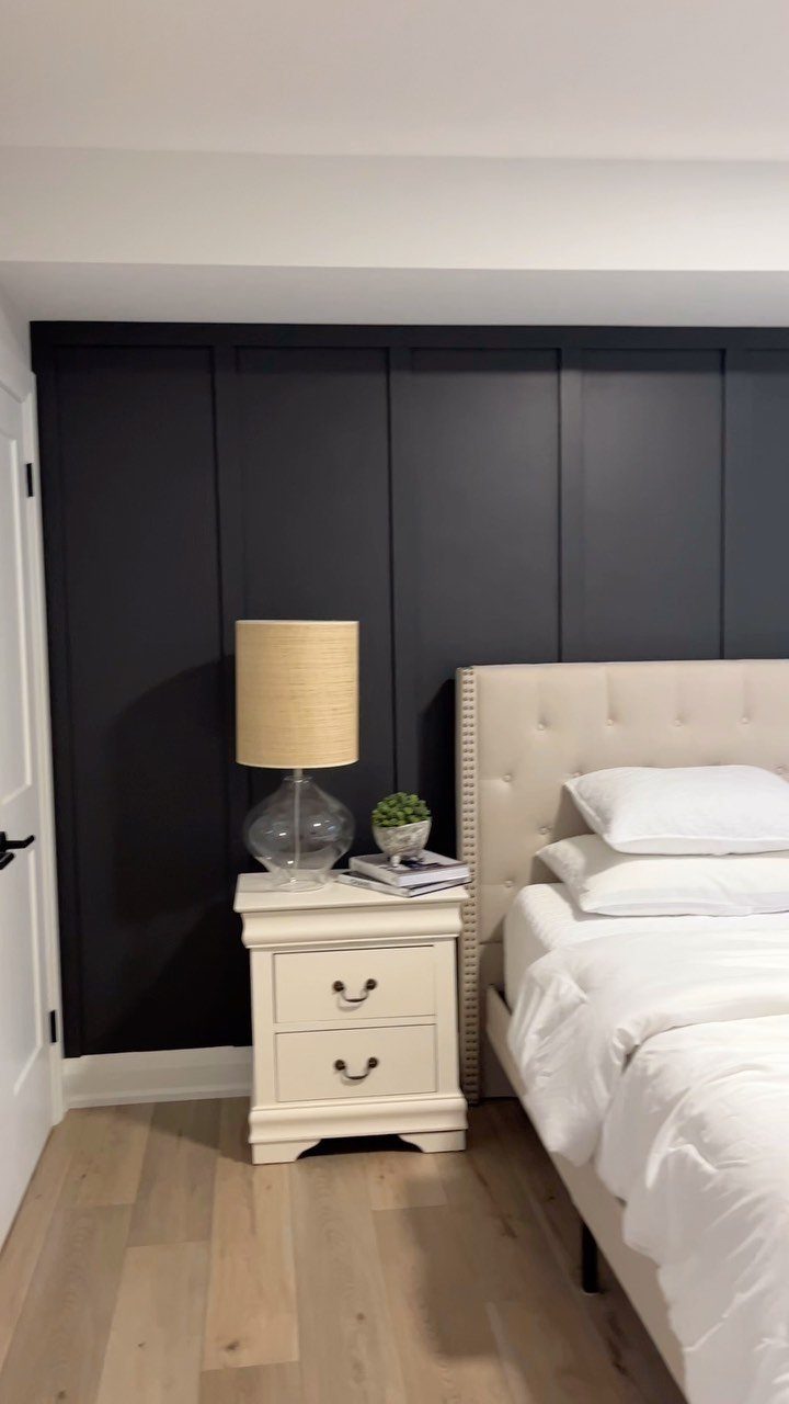 Wall Moulding Design: 11 Styles That Work in Every Room 1 Dark grey board and batten wall moulding behind a white nightstand and bed.