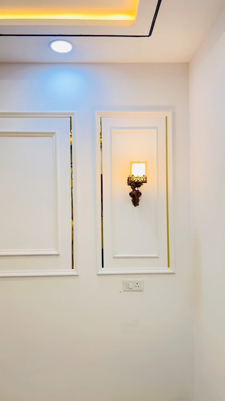 Wall Moulding Design: 11 Styles That Work in Every Room 9 White wall mouldings with gold trim and a decorative wall sconce on a white wall.