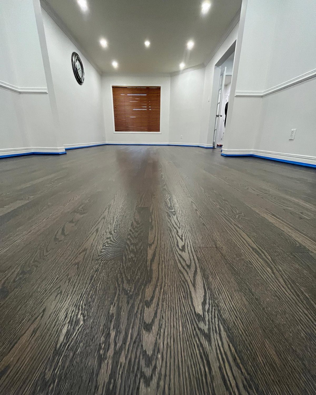 Dark wood plank flooring with prominent grain stretching across a room with white walls.