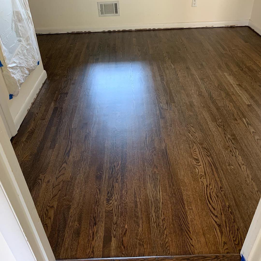 Dark brown stained oak hardwood flooring installed in a room with white walls and baseboards.