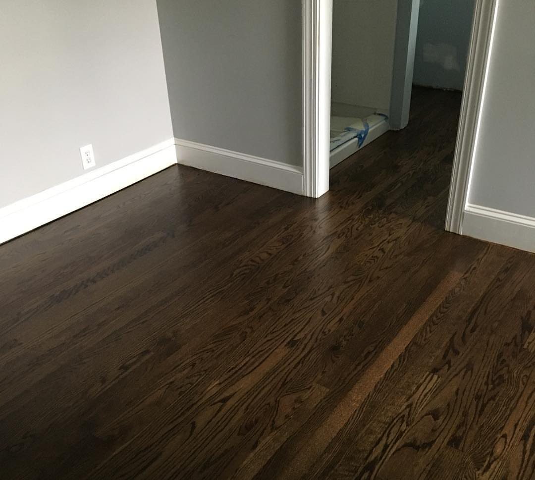 Dark brown stained oak hardwood flooring installed in a room with white baseboards.