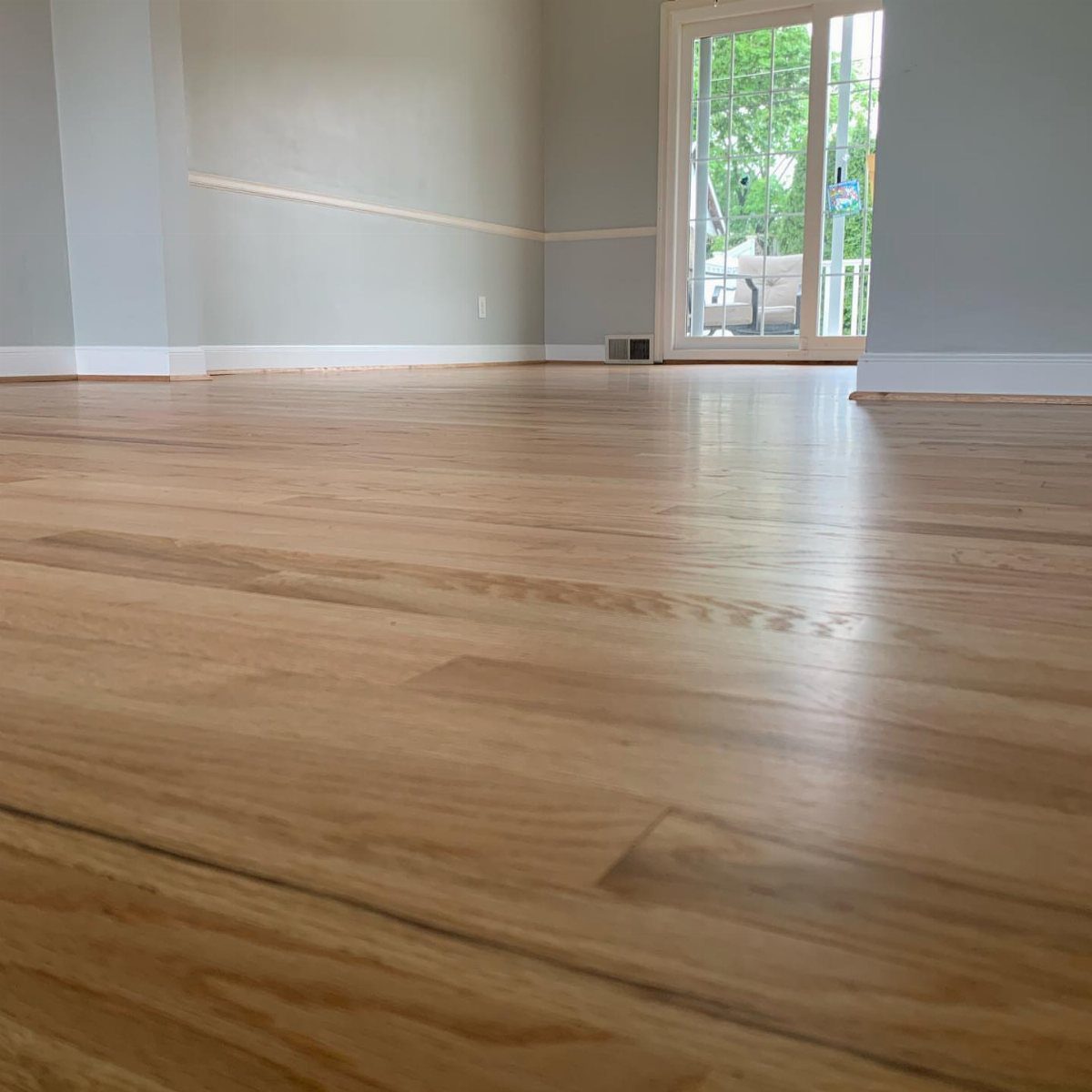 Light ginger stained oak hardwood flooring in a bright, modern room with gray walls.