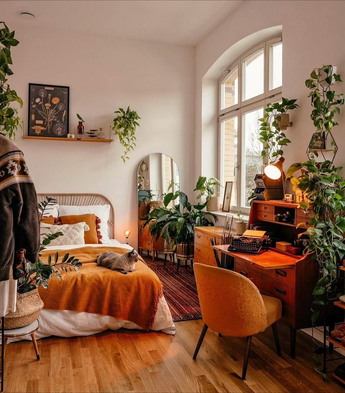 Orange Wood Floors: 4 Smart Style Ideas That Work 4 A cozy bedroom with orange wood floors, warm bedding, and many lush green houseplants throughout the room.