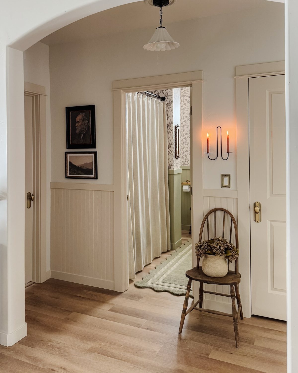 Cream beadboard wainscoting in a bright hallway with light wood floors and a wooden chair.