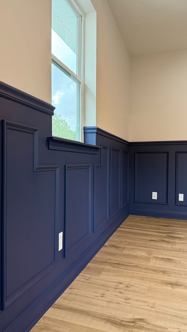 Navy blue paneled wainscoting installed on a hallway wall with light beige upper walls.