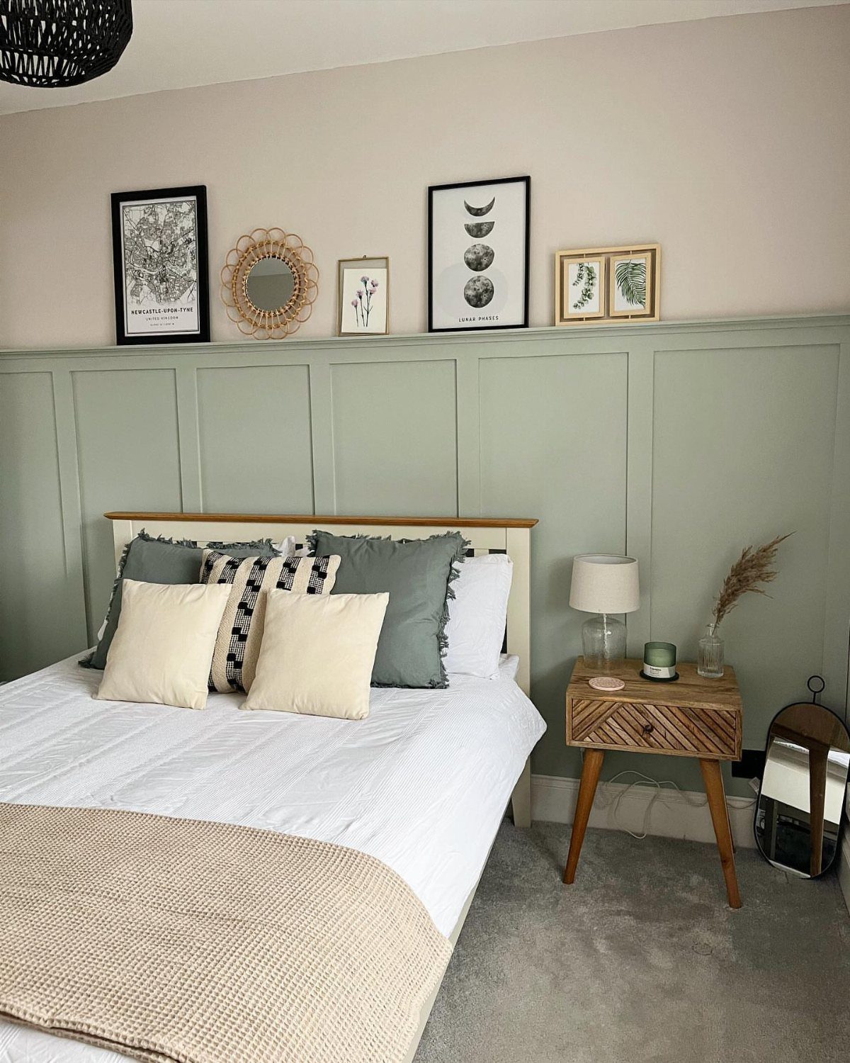 Sage green board-and-batten wainscoting installed on a bedroom wall behind a bed.