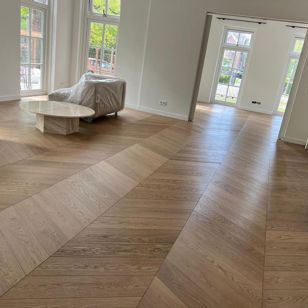 Diagonal patterned hardwood flooring in a bright, modern living room with large windows.