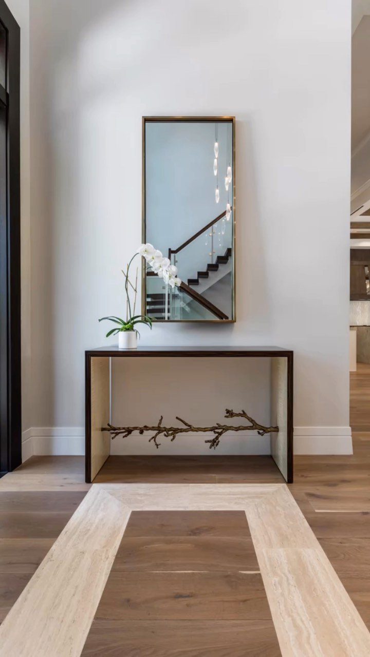 Light and dark wood flooring with an inlaid border pattern in a modern hallway.
