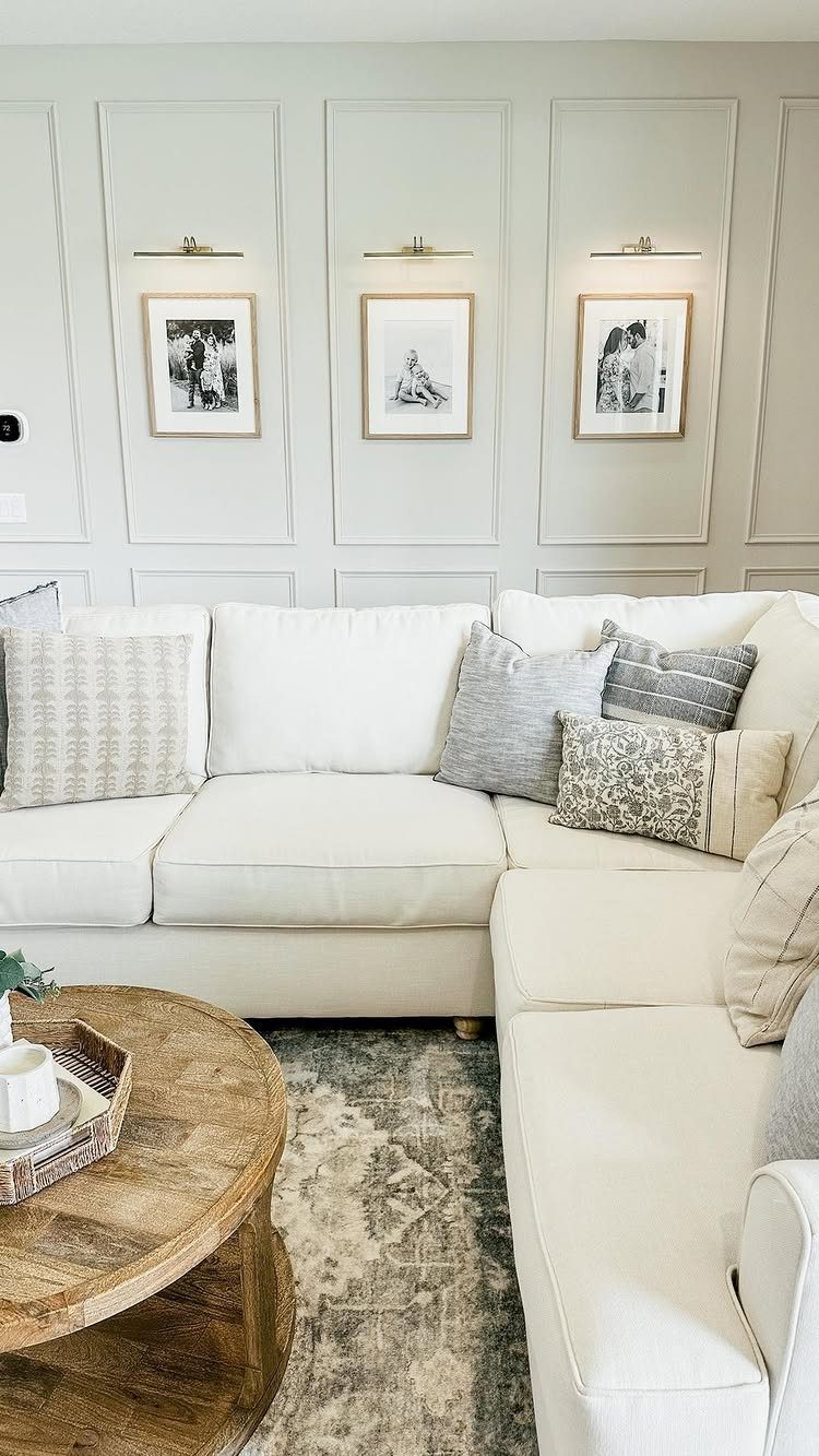 Decorative wall molding panels with framed art and gold picture lights above a white sofa.
