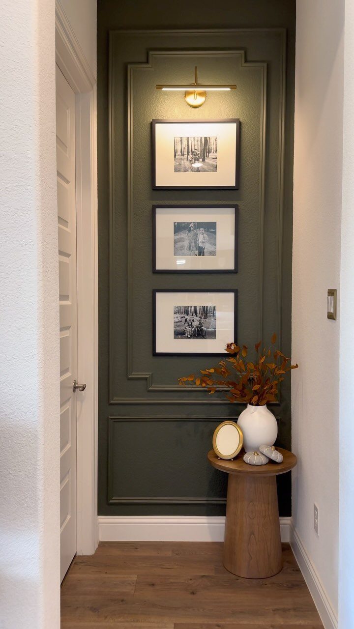 Dark olive green accent wall with decorative molding and three framed landscape photographs hanging vertically.
