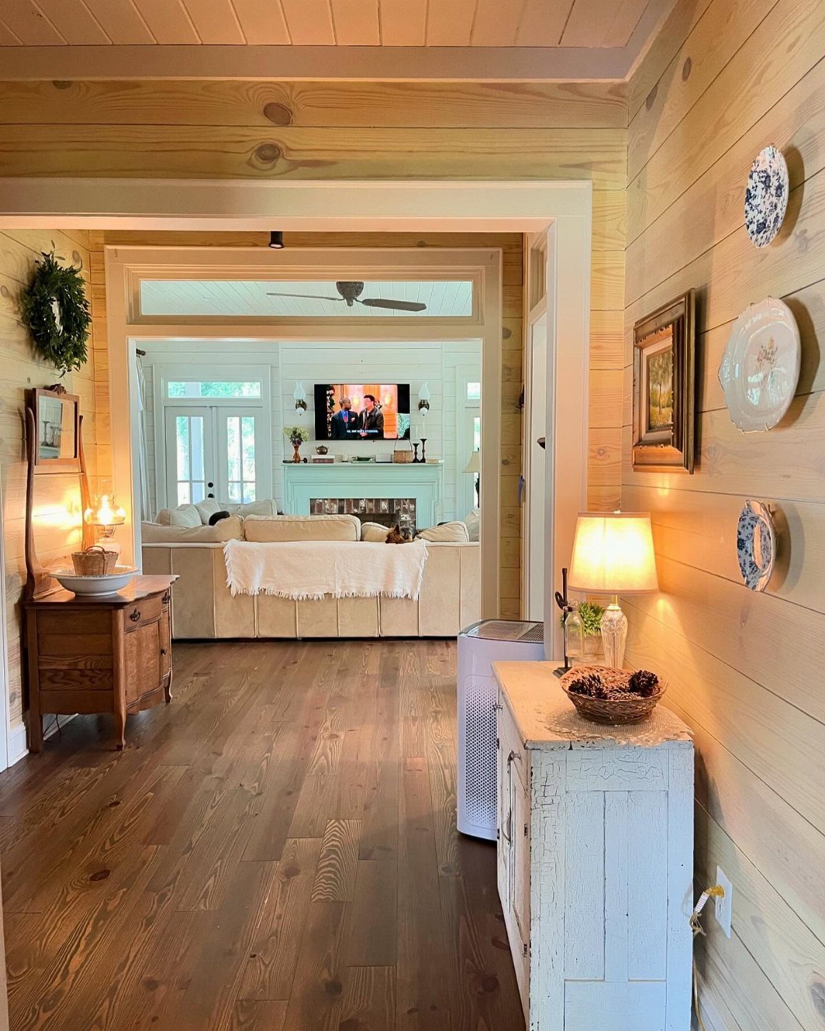 Natural wood shiplap walls and ceiling in a hallway leading to a bright living room.